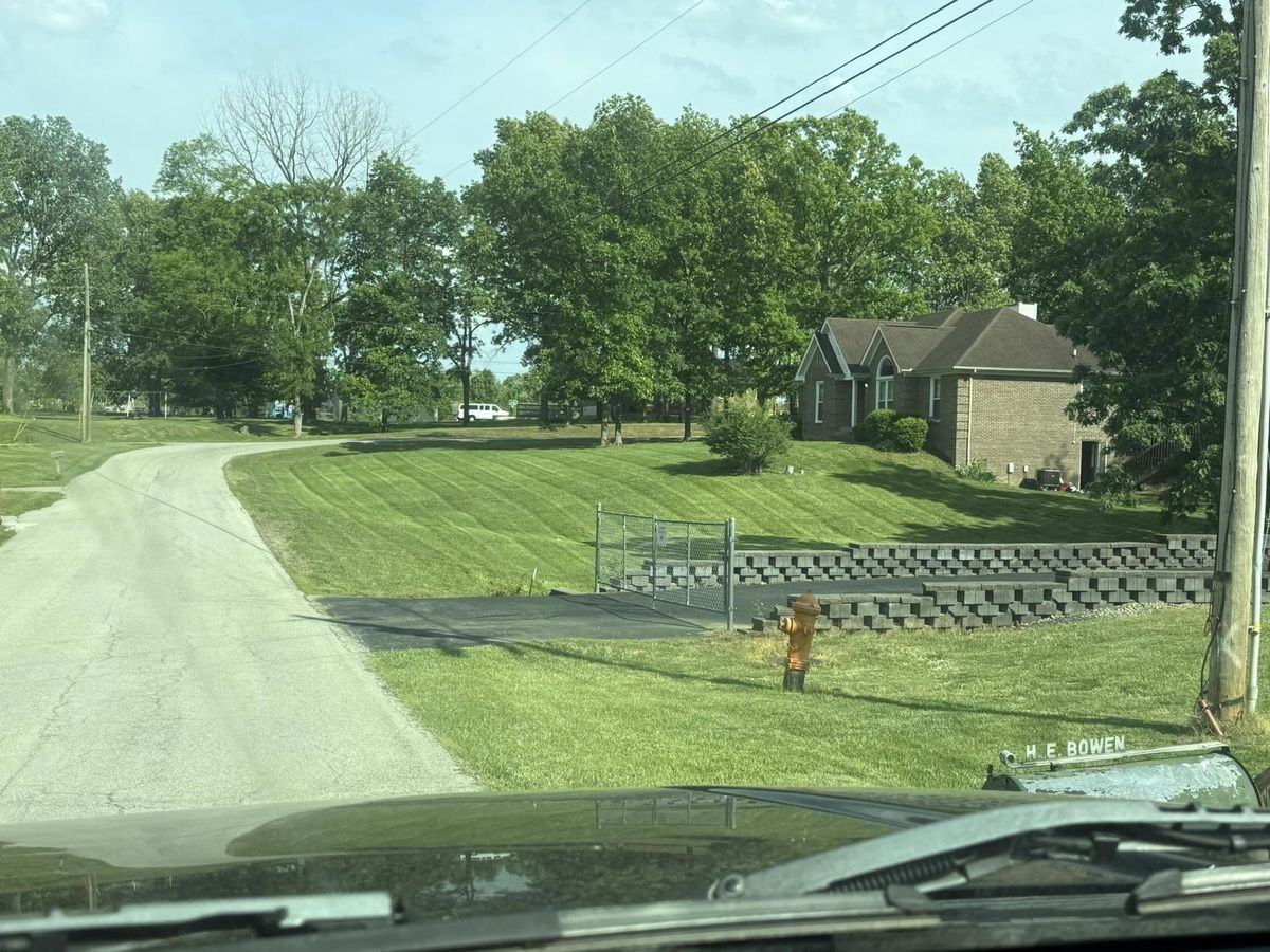 A gated property with mown ground running back toward the treeline, seen from the truck.